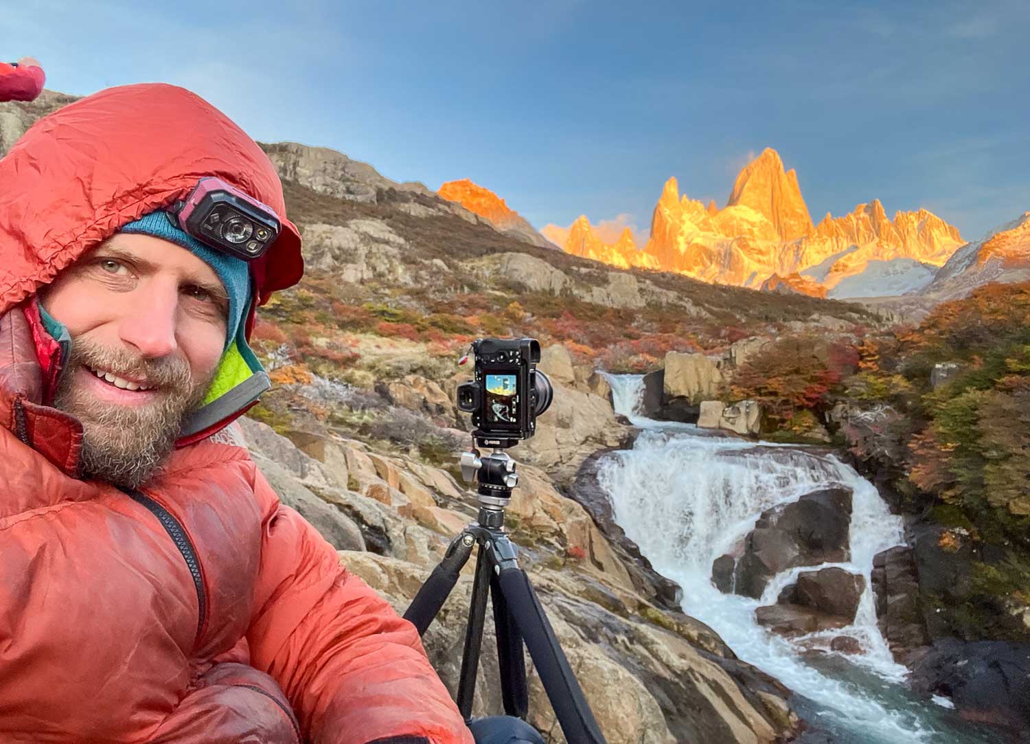 Photo of a photographer with his tripod by a mountain stream