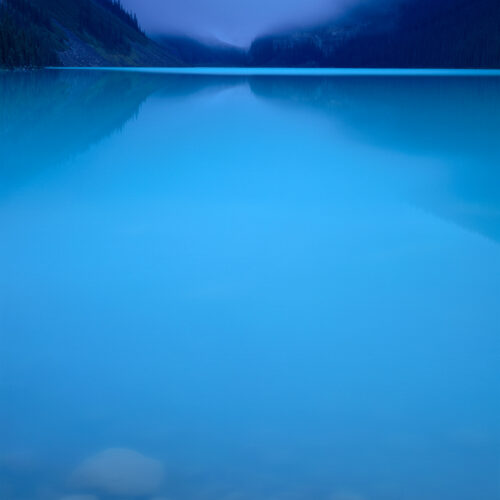Banff National Park, Canada Dawn at Lake Louise brings glass calm waters and morning fog.