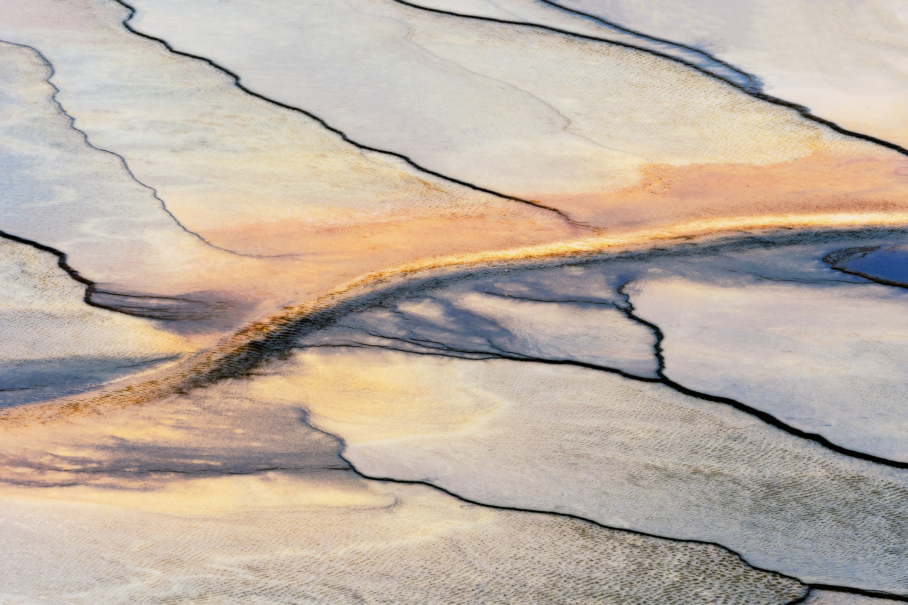 Yellowstone National Park, Wyoming Orange bacterial mats in an outflow channel of Grand Prismatic Spring stretch across the terraces in the Midway Geyser Basin.