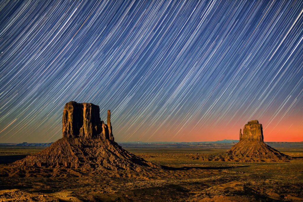 A long exposure photograph with stars lighting like strands in the sky in Monument Valley in Arizona
